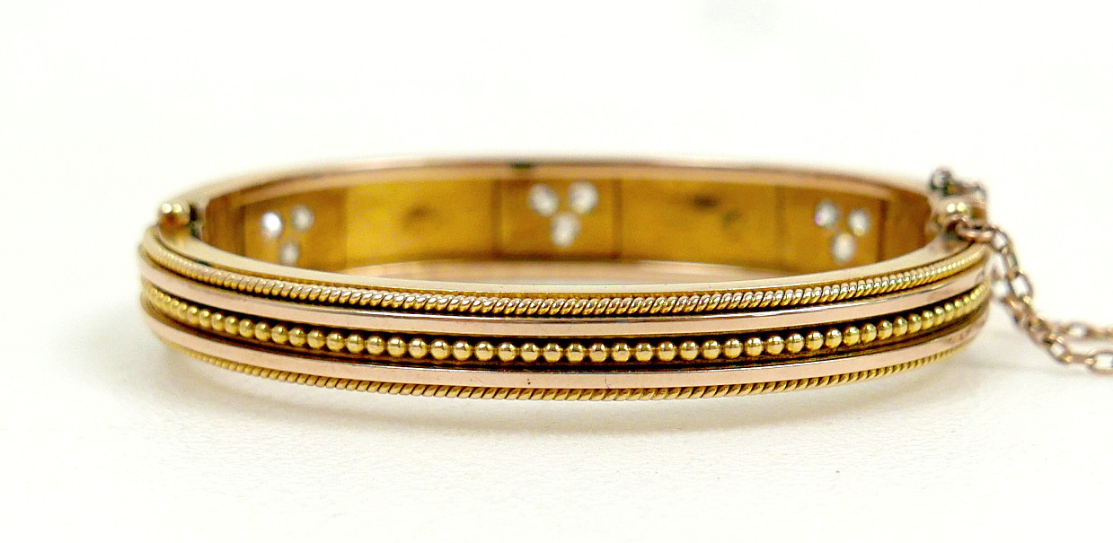 A 19TH/EARLY 20TH CENTURY YELLOW METAL AND DIAMOND HINGED BANGLE.