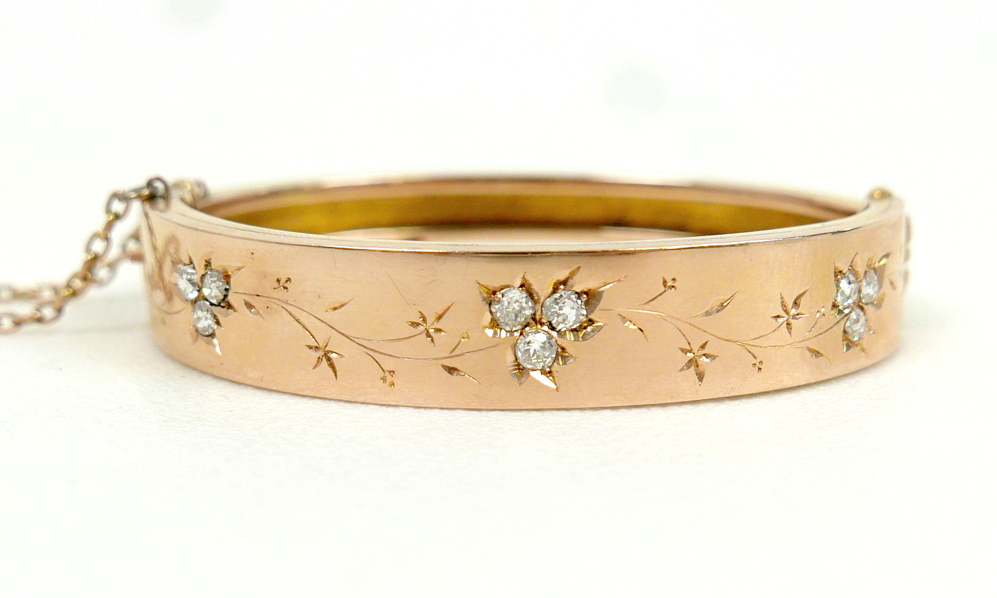 A 19TH/EARLY 20TH CENTURY YELLOW METAL AND DIAMOND HINGED BANGLE.
