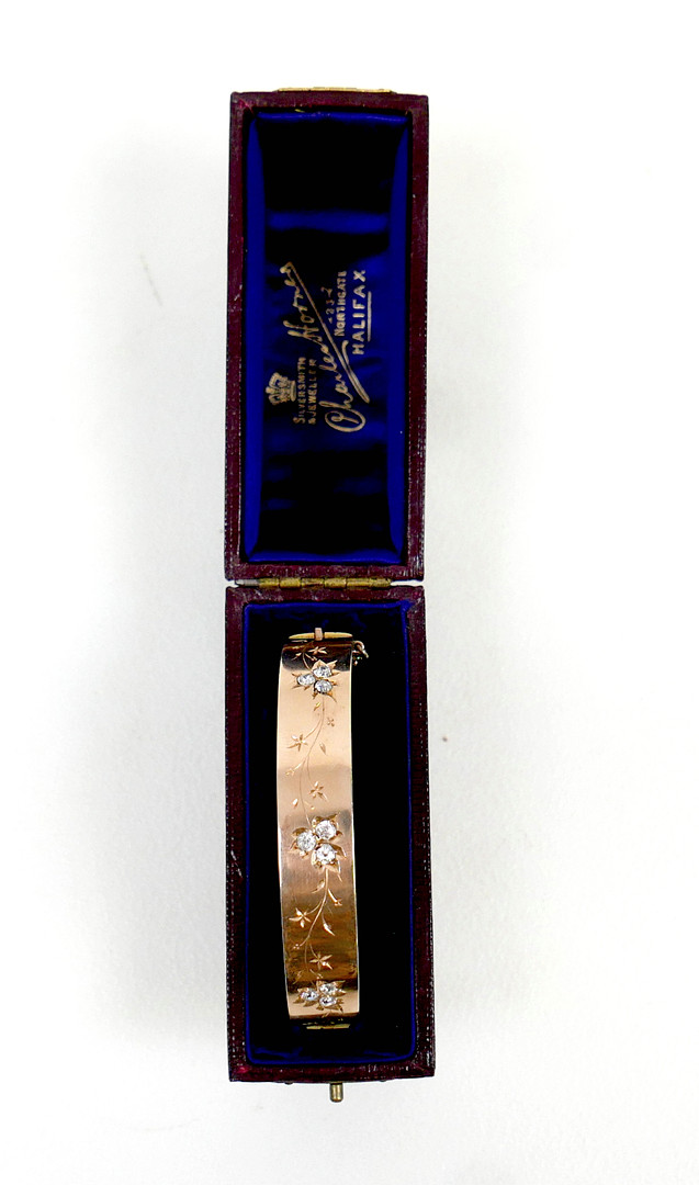 A 19TH/EARLY 20TH CENTURY YELLOW METAL AND DIAMOND HINGED BANGLE.