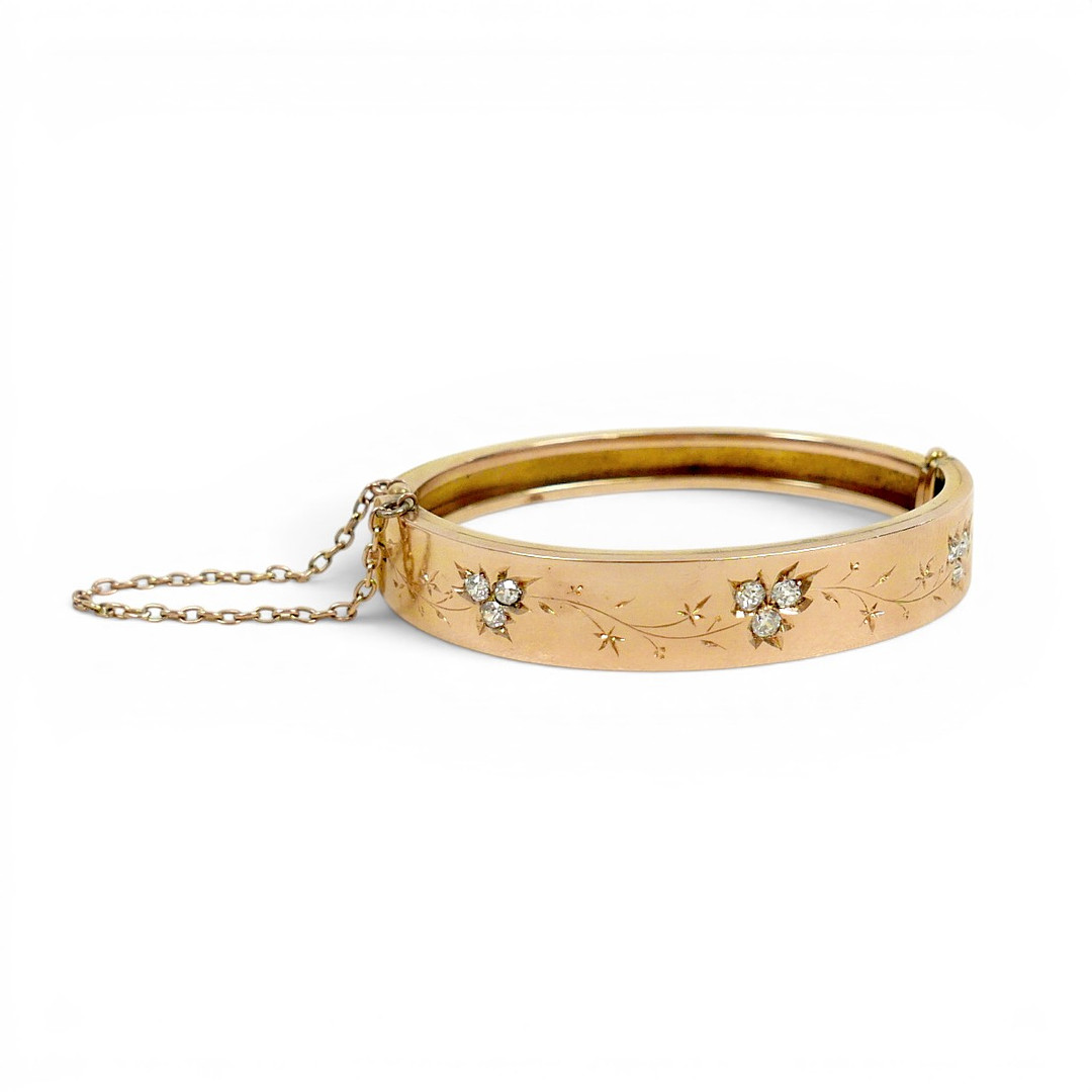 A 19TH/EARLY 20TH CENTURY YELLOW METAL AND DIAMOND HINGED BANGLE.