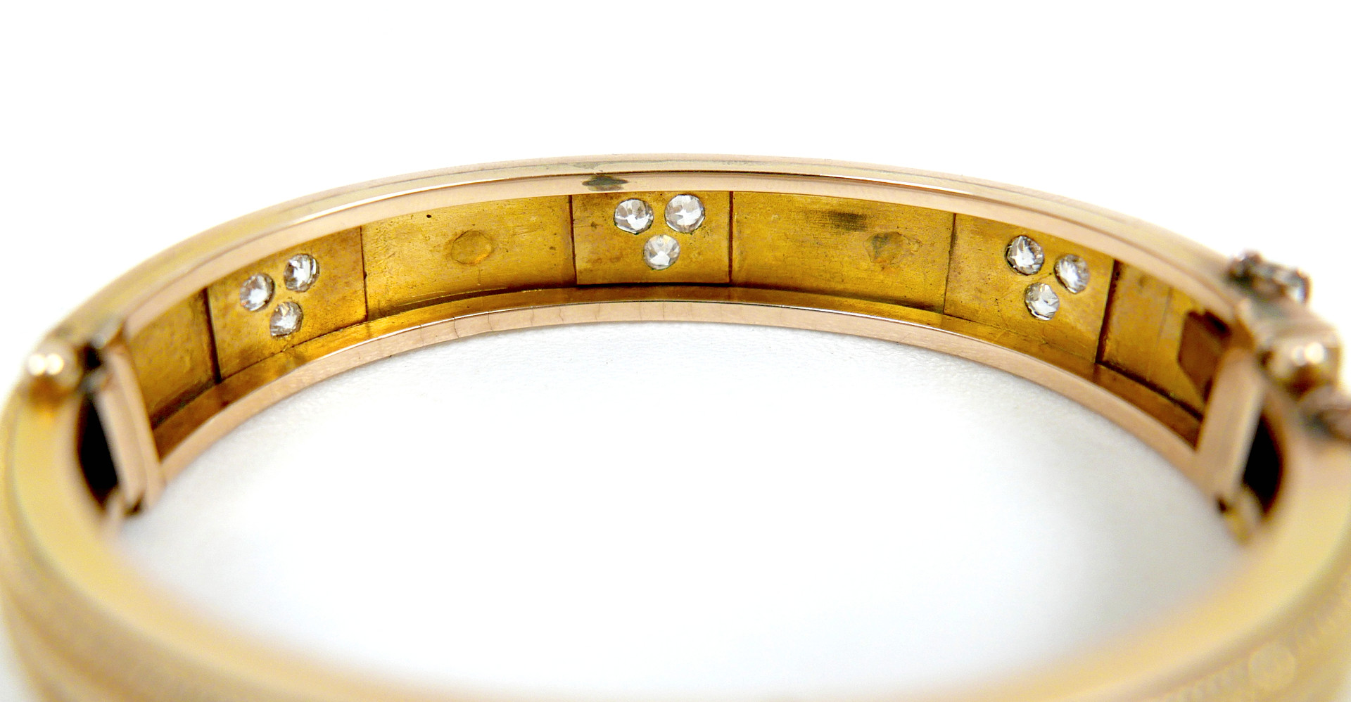 A 19TH/EARLY 20TH CENTURY YELLOW METAL AND DIAMOND HINGED BANGLE.