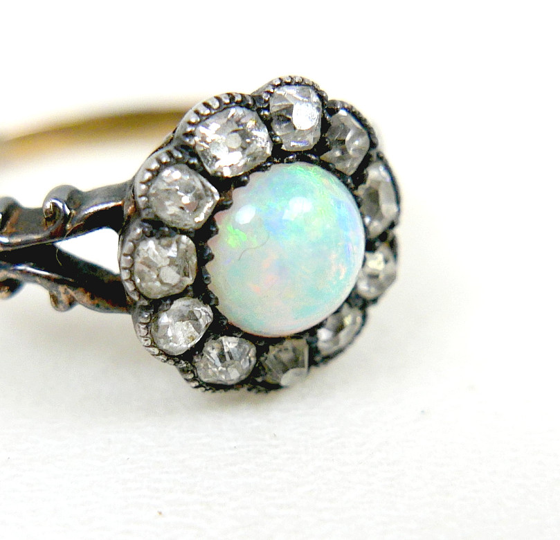 AN 18CT GOLD OPAL AND DIAMOND DAISY RING.
