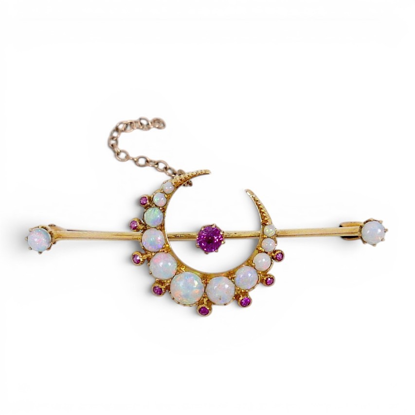 A 15CT GOLD OPAL AND RUBY CRESCENT FORM BAR BROOCH.