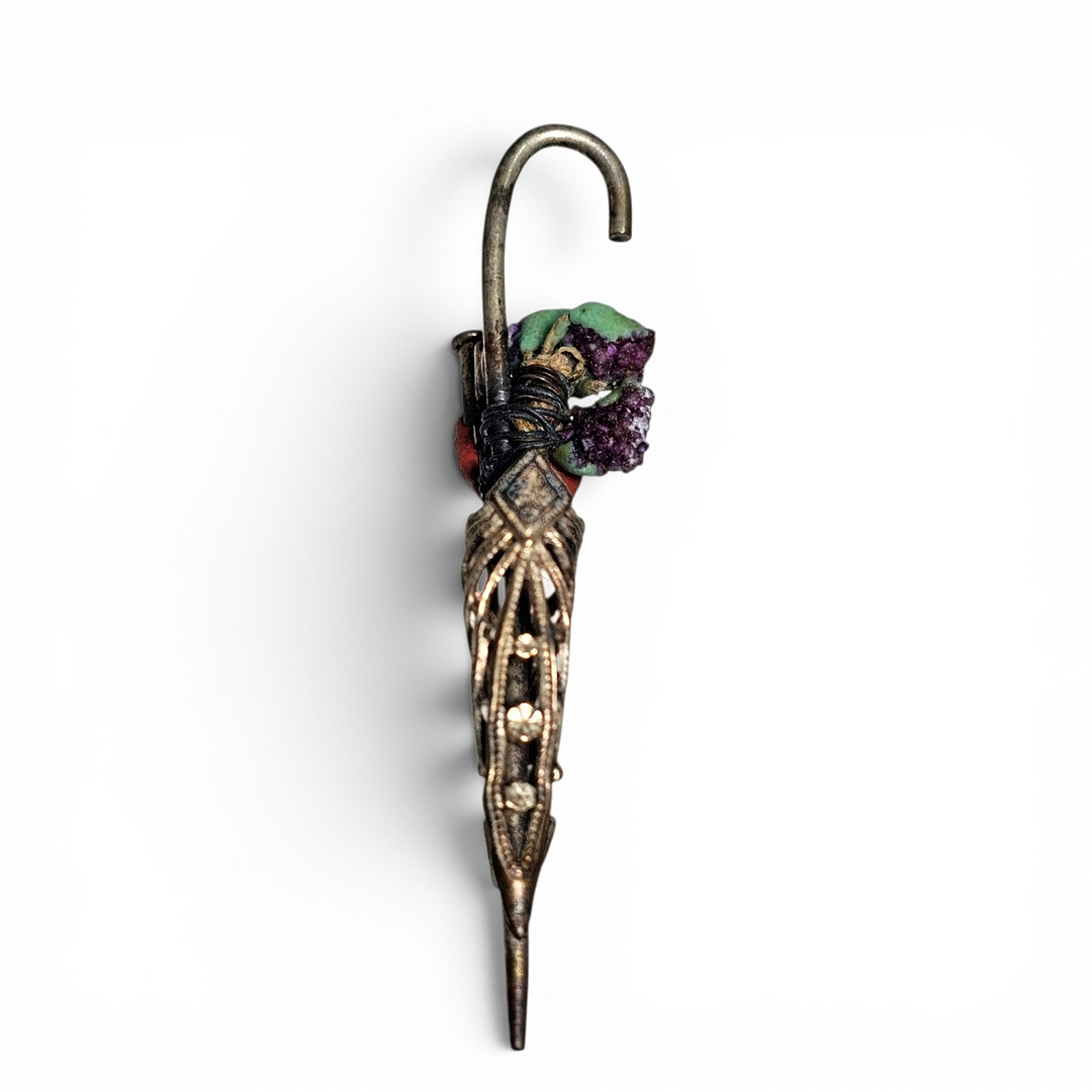 Broche a modo de paragüas en plata calada con detalle de piedras.