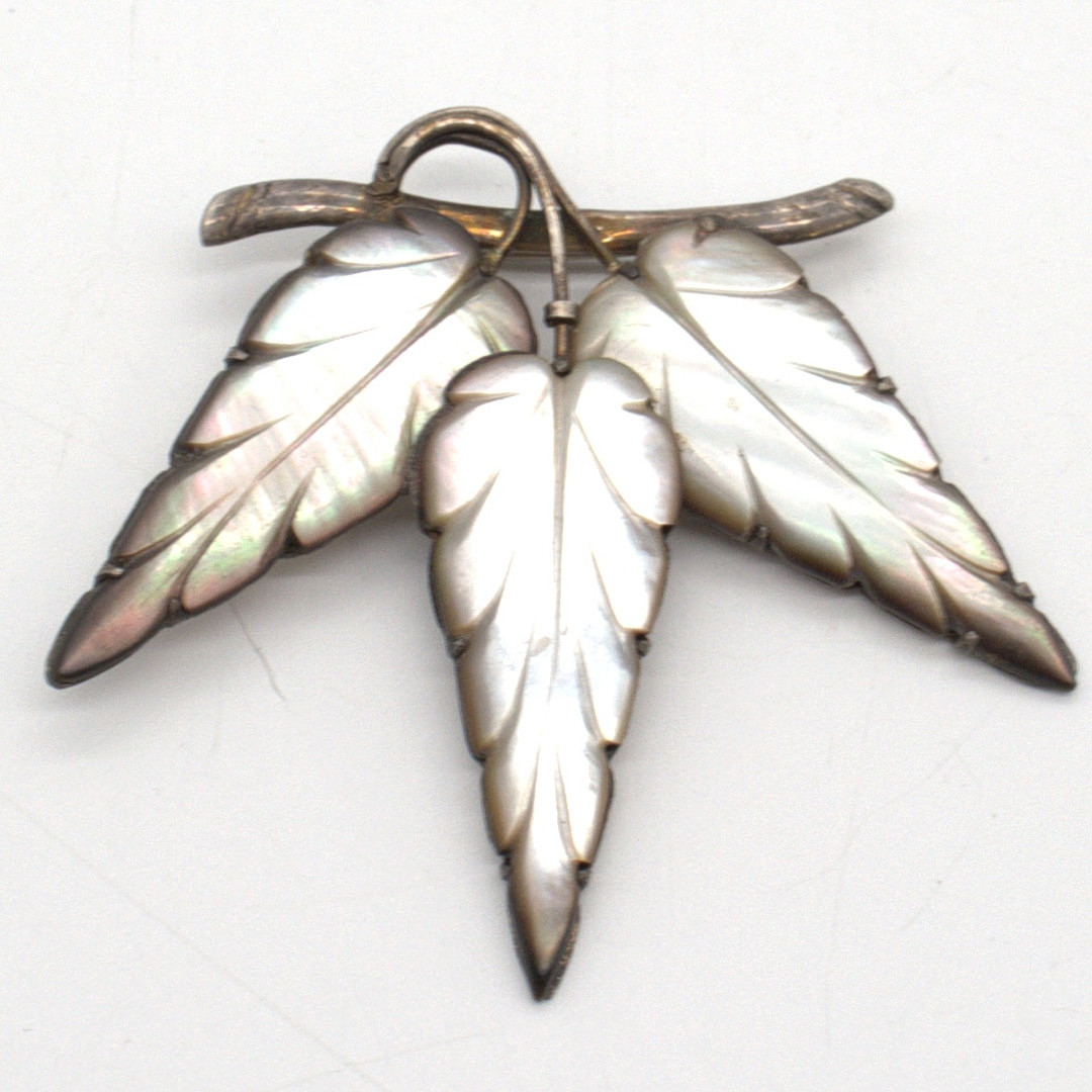JUGENDSTIL 800 SILBER BROSCHE, HANDARBEIT, BESETZT MIT GESCHNITZTEN PERLMUTT EINLAGEN IN FORM EINES ZWEIGS MIT STILISIERTEN BLÄTTERN UM CA. 1900.