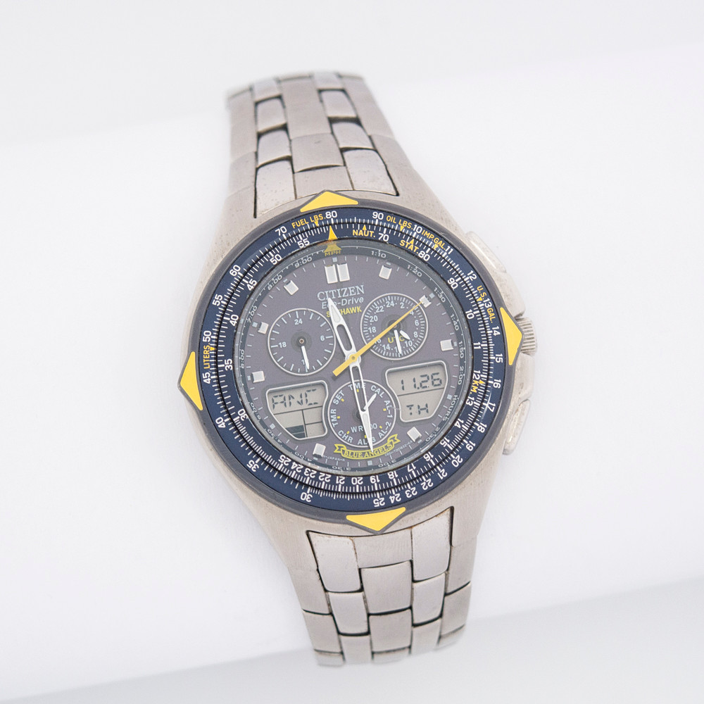 CITIZEN SKYHAWK ECO-DRIVE "BLUE ANGELS", QUARTZ, DREHBARE LÜNETTE, ANALOGES, DIGITALES LCD-DISPLAY, LEUCHTZEIGER, UHRZEIT UND DATUM FÜR 30 WICHTIGE STÄDTE WELTWEIT, 12-STUNDEN-ANZEIGE, 24-STUNDEN-ANZEIGE, ZIEH-/DRÜCK, GEHÄUSE UND ARMBAND AUS TITANIUM.