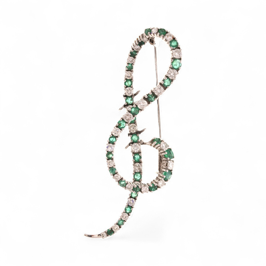 Treble clef-shaped diamonds and emeralsd brooch.