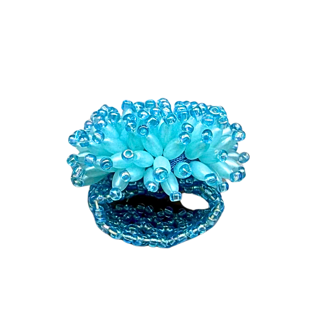 ELASTISCHER STOFFRING MIT HELLBLAUEN, OVALEN KUNSTSTOFFPERLEN ALS DEKOR.