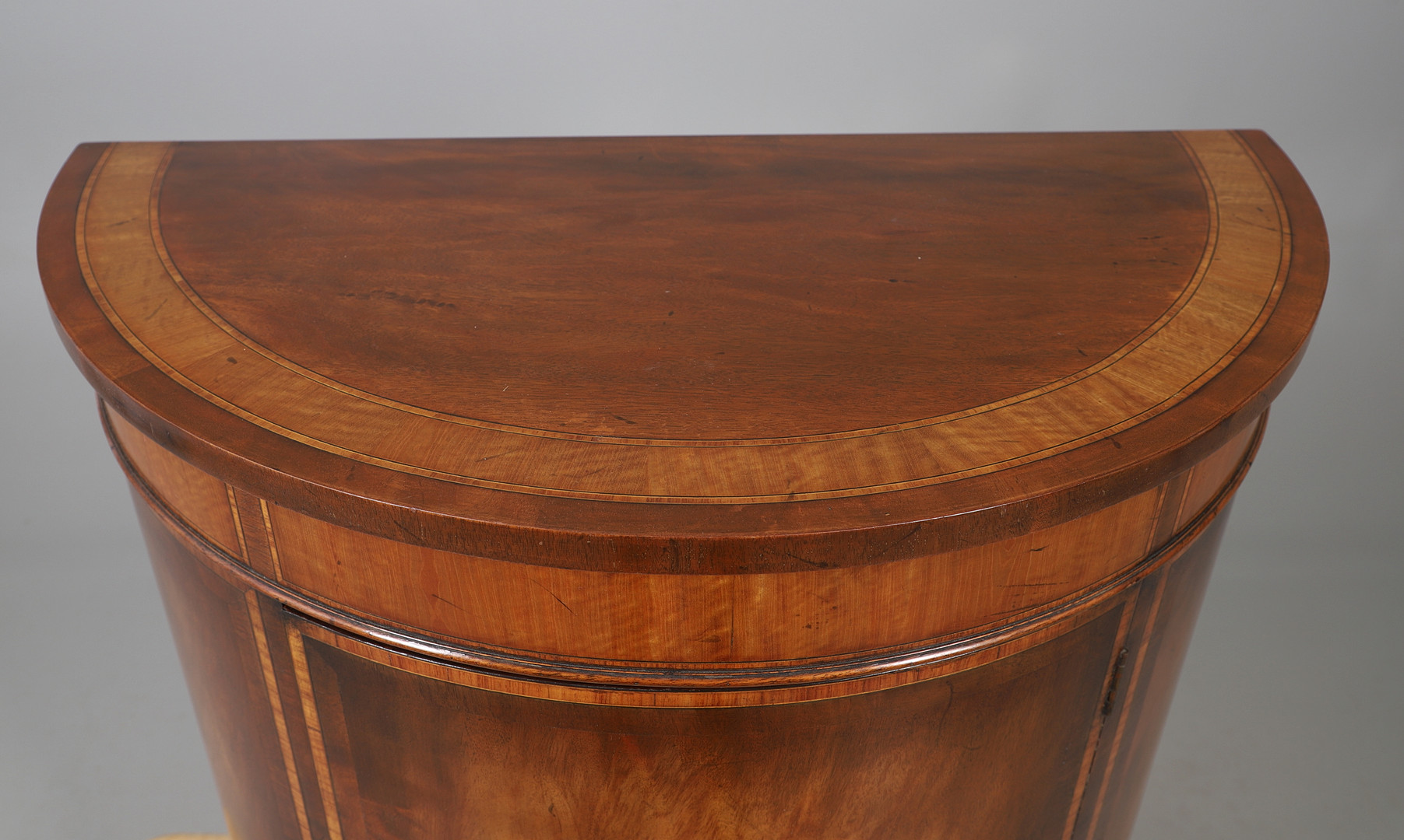 AN INLAID MAHOGANY DEMILUNE CUPBOARD.