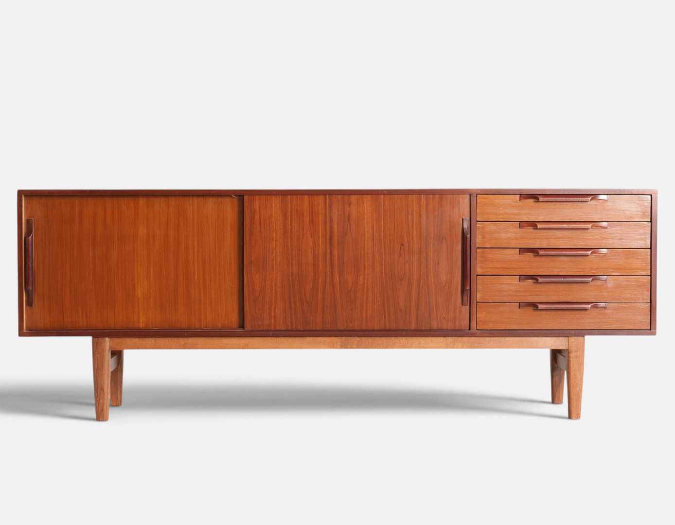 Lav skænk af teak, front med skuffer og skydelåger bag hvilke hylder, tilspidsede ben. Mid-Century Modern Design af nyere dato.