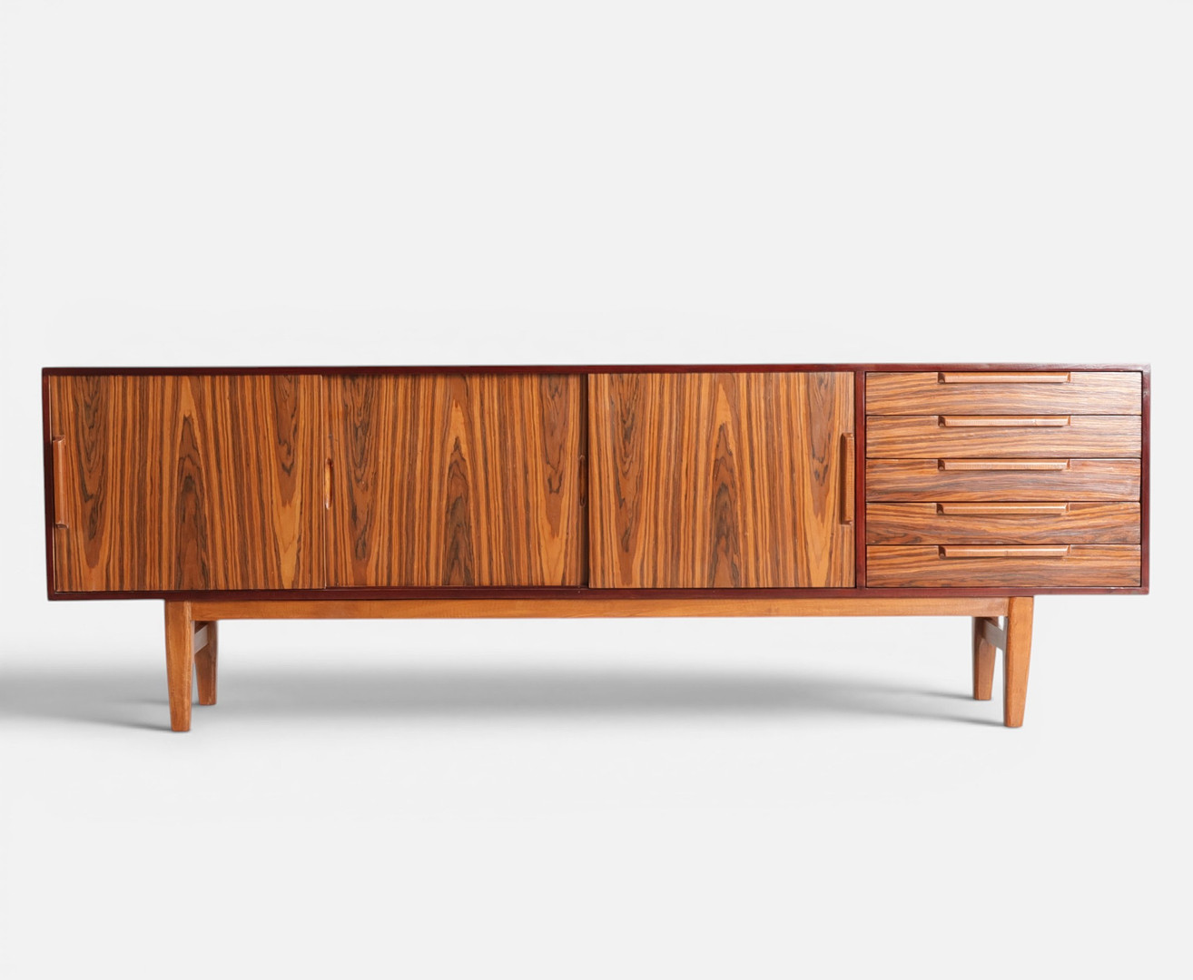 Lav skænk af teak, front med skuffer og skydelåger bag hvilke hylder, tilspidsede ben. Mid-Century Modern Design af nyere dato.