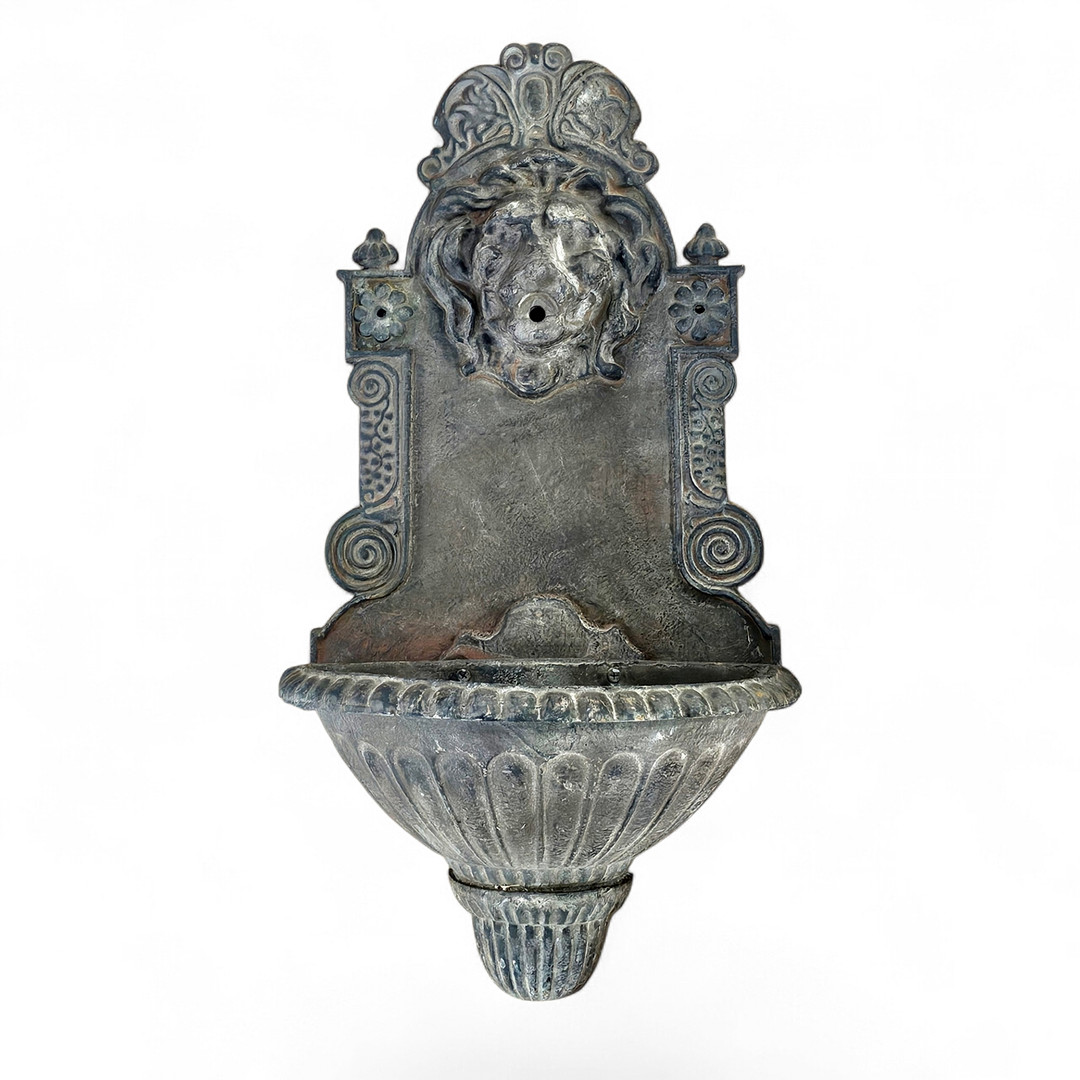 Fuente en hierro con forma de cabeza de león.