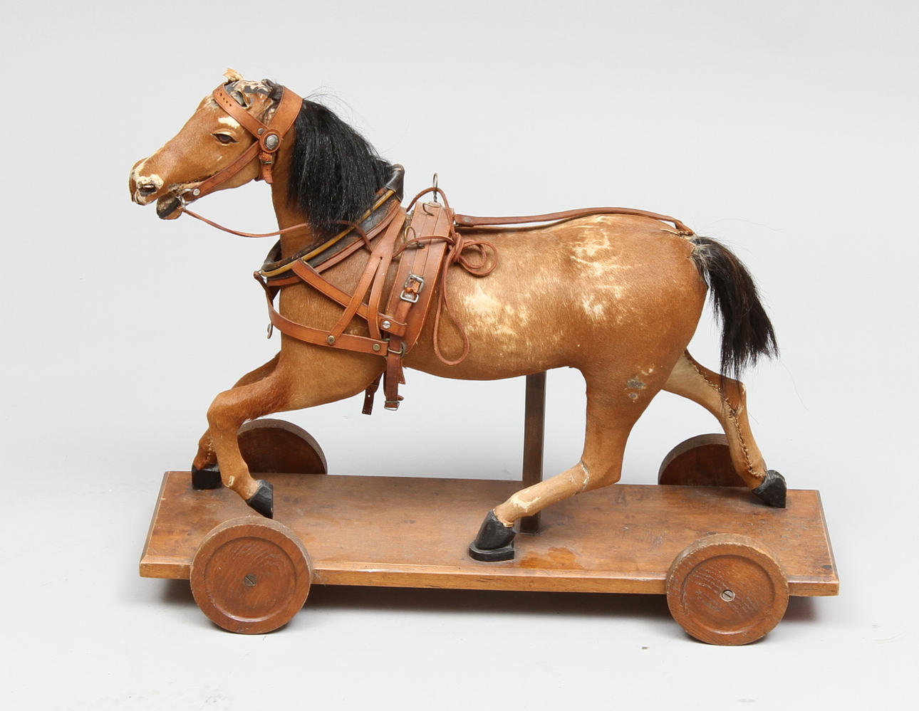 GEMLA LEKSAKSHÄST 1930-tal, skinnklädd med seldon, träplatta med hjul.