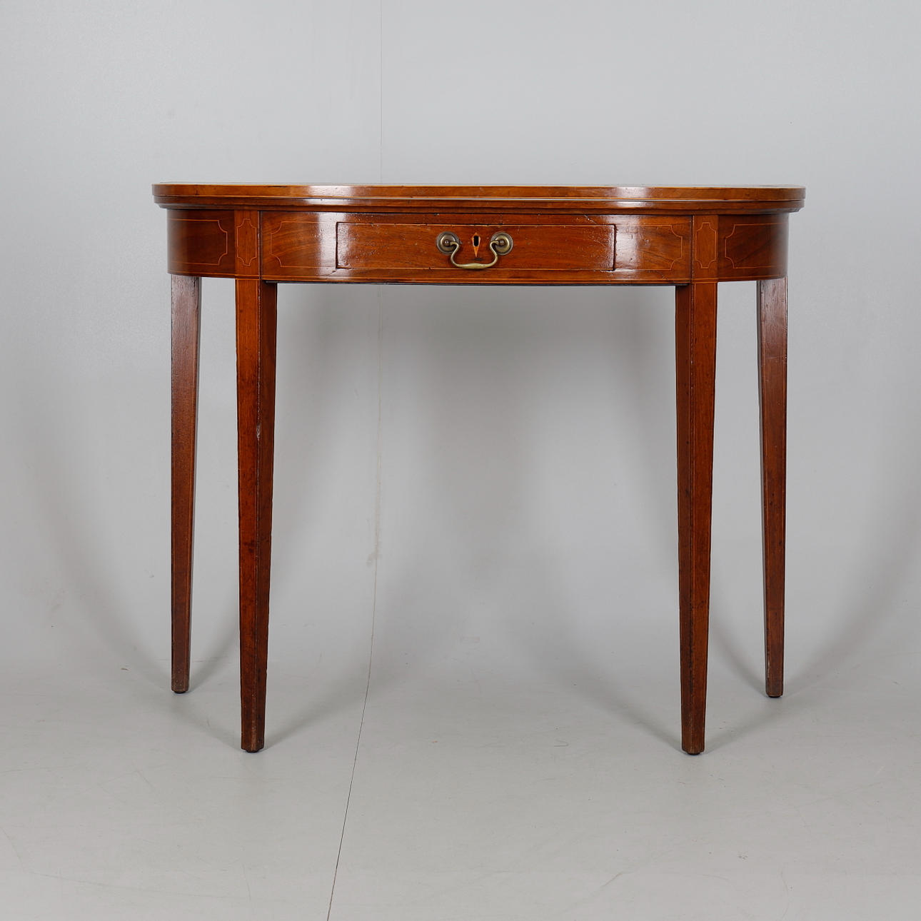 UNA MESA DE TÉ DEMI-LUNE DE CAOBA.