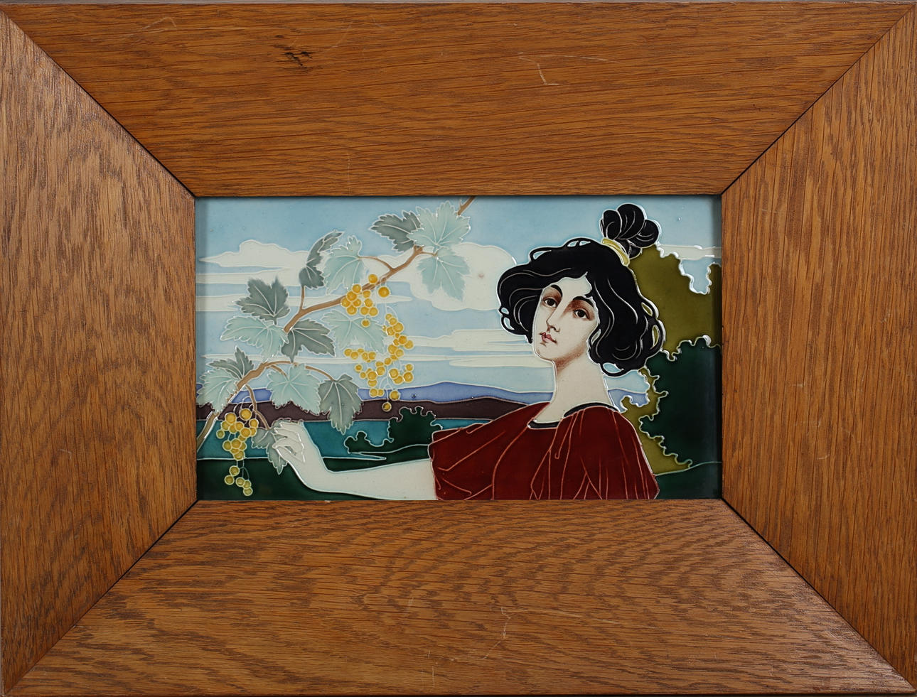 OIDENTIFIERAD KONSTNÄR. Kvinna med vindruvekvist i jugentstil, 1900-talets början. Keramikplatta. Prägelsignerad tergo C H eller G H.