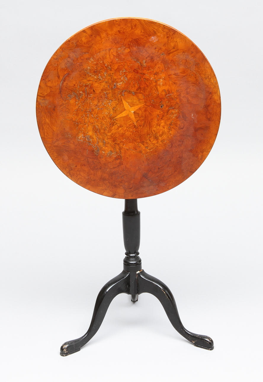 FÄLLBORD, rund skiva i rotfanér med dekor av stjärna, svärtad fot, brännstämplat AAS, tidigt 1800-tal.