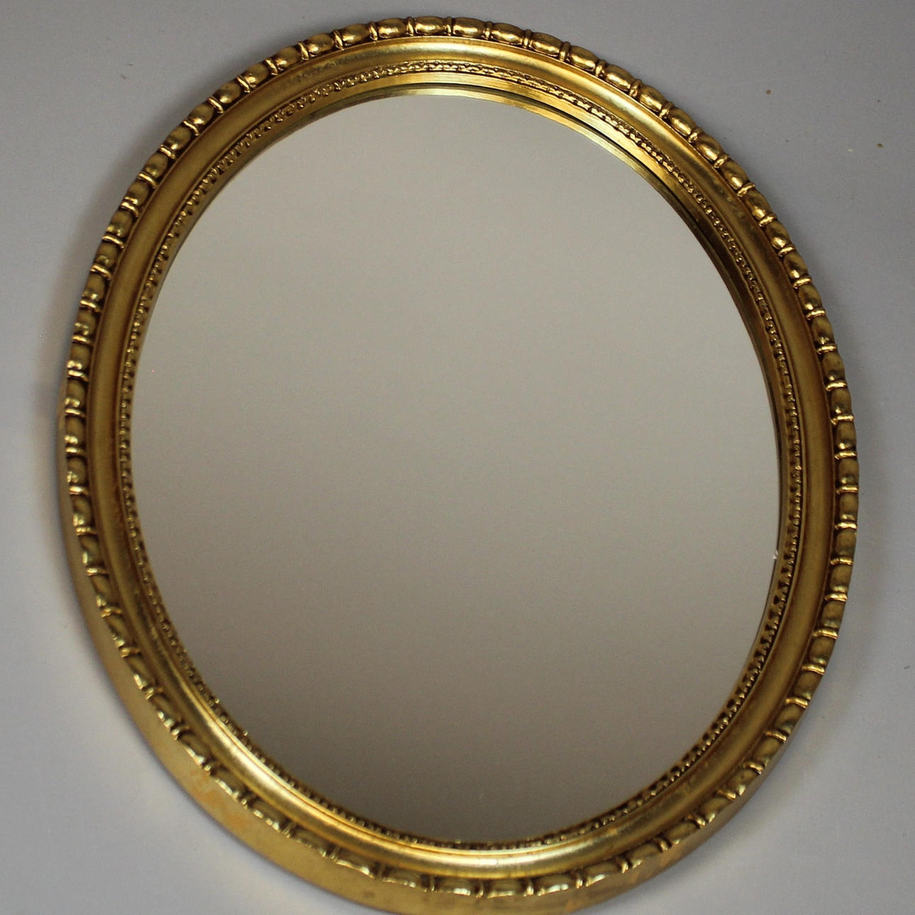 SPIEGEL, oval mit goldfarbenem Rahmen.