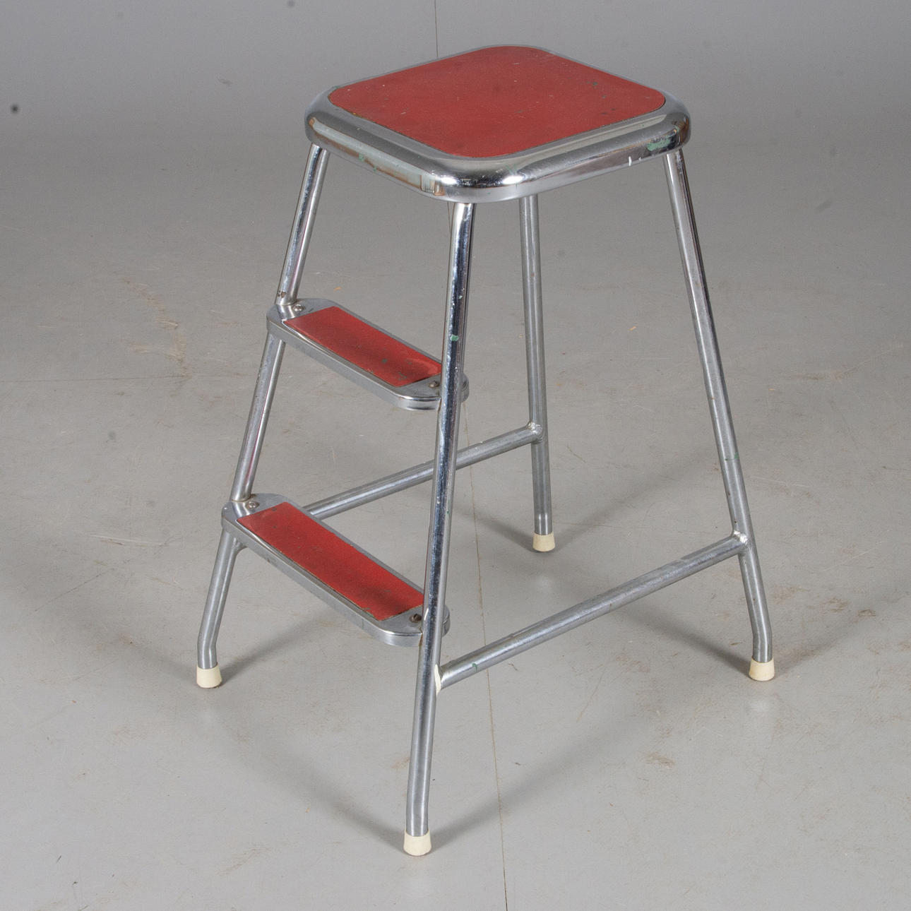 TRAPPALL, kromad metall med röda trappsteg.