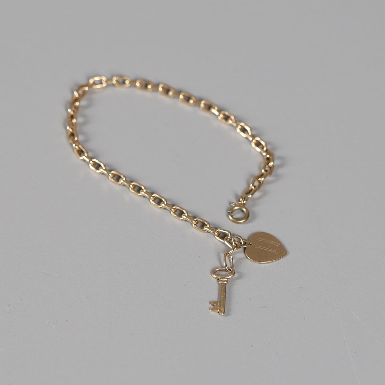 ET GULD OPEN LINK ARMBÅND MED HJERTE OG NØGLECHARM.