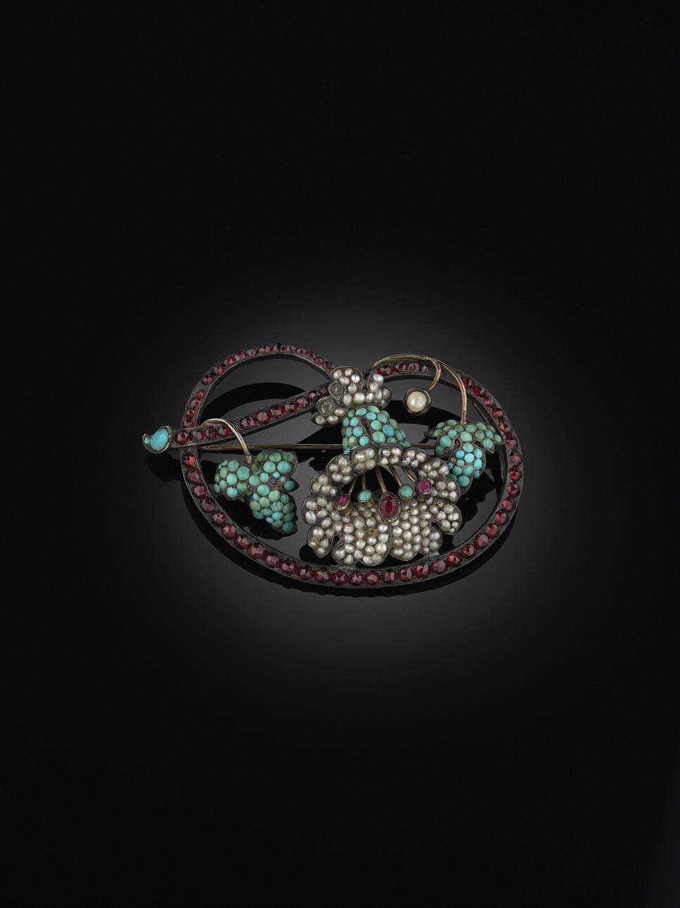 BROSCH, silver och delvis förgylld med små turkoser (två saknas), granater, halvpärlor (två pärlor saknas), 2 små rosa safirer och glas.