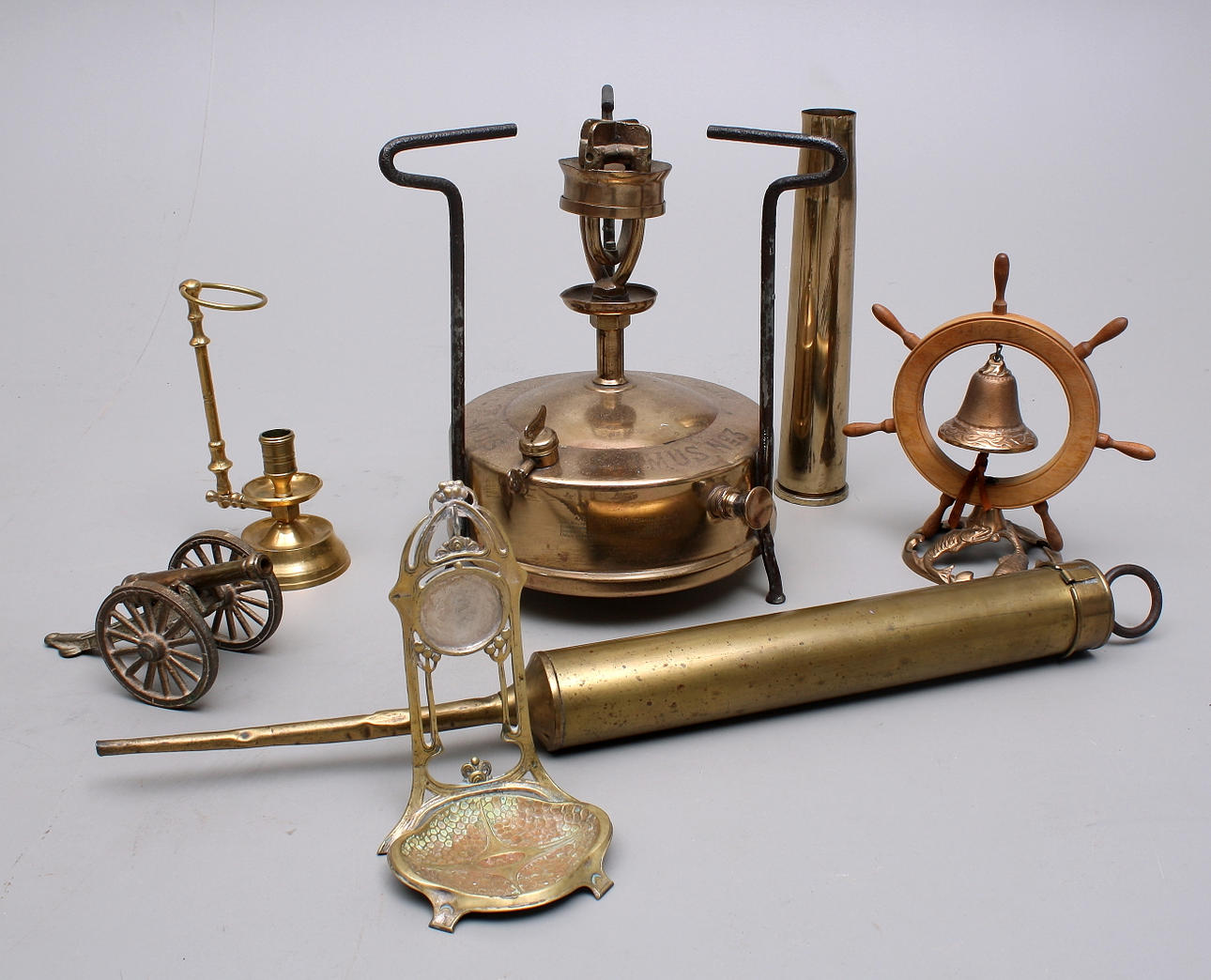 MÄSSINGSFÖREMÅL, Primuskök + oljespruta + skeppsklocka + klockställning jugend + patronhylsa + bordskanon + ljusstake.