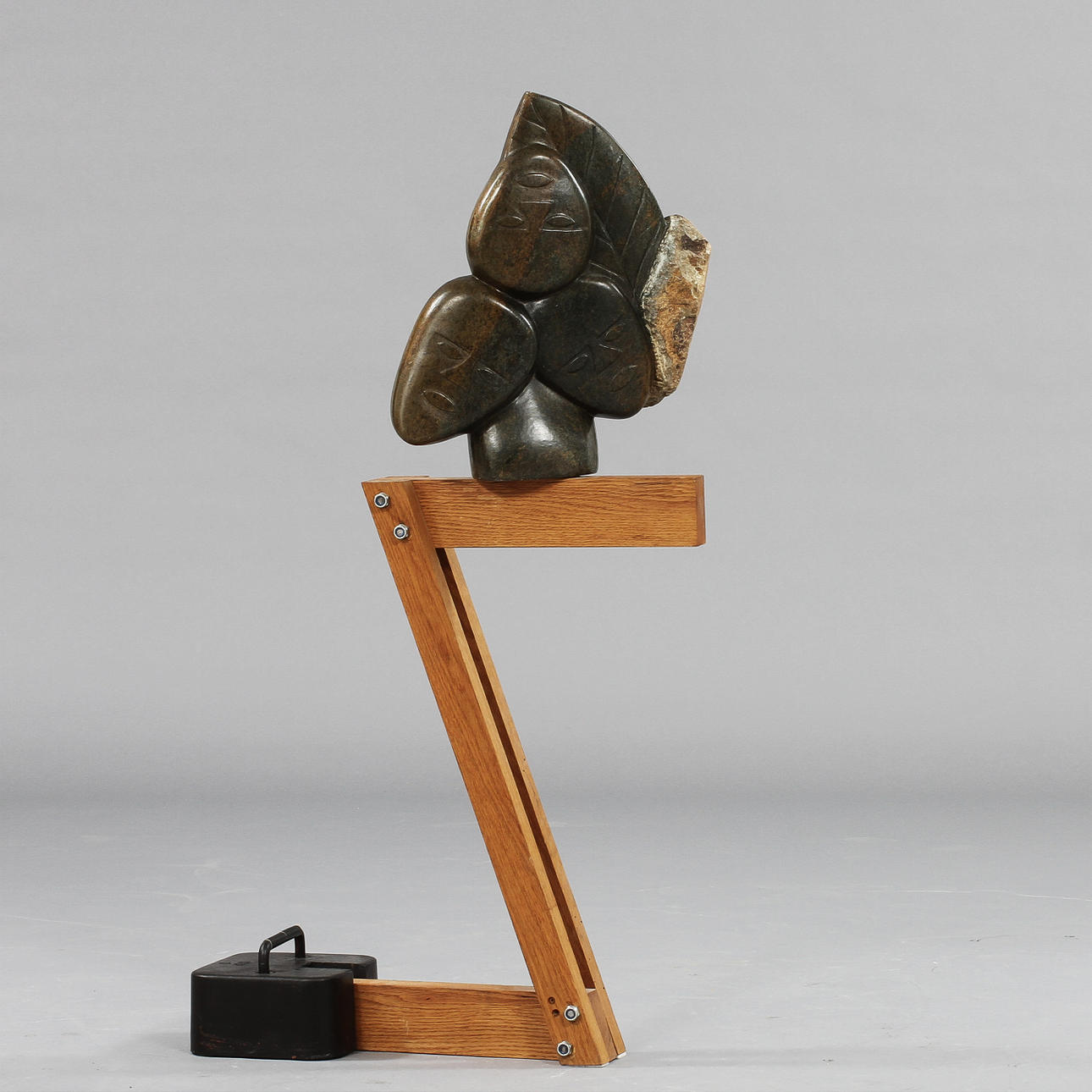 OKÄND KONSTNÄR. Skulptur, sten med dekor av ansikten monterad på träställning och järnsockel.