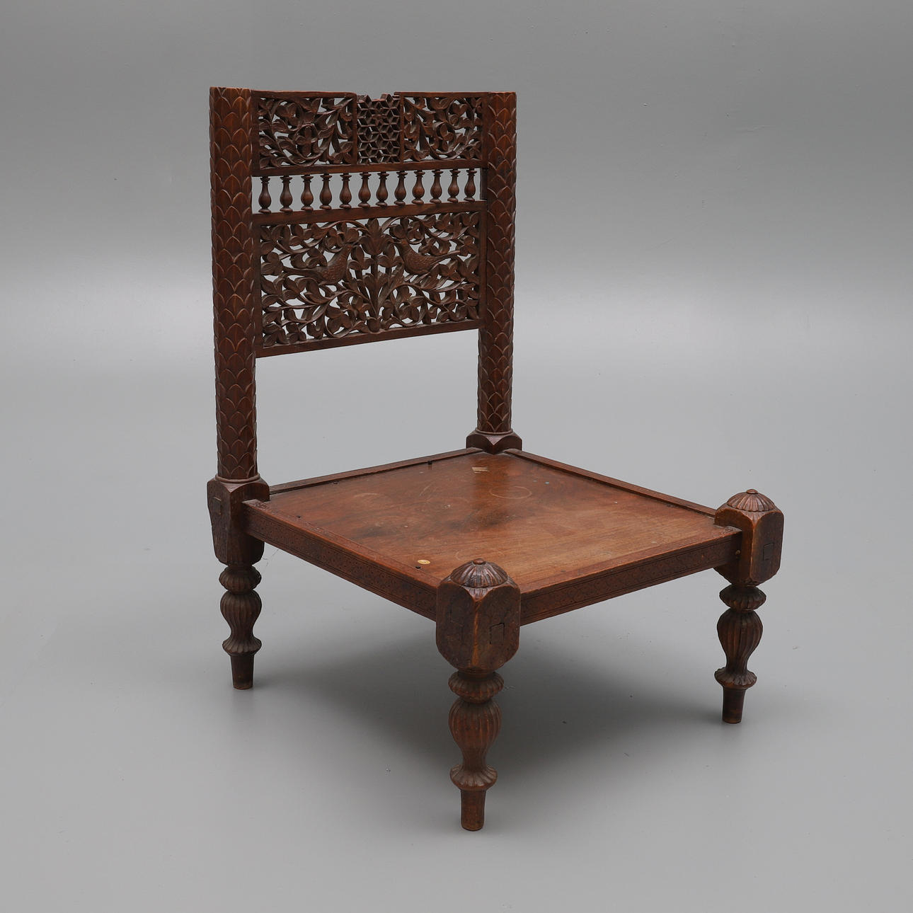 UNA SILLA BAJA DE TECA DE LA INDIA.