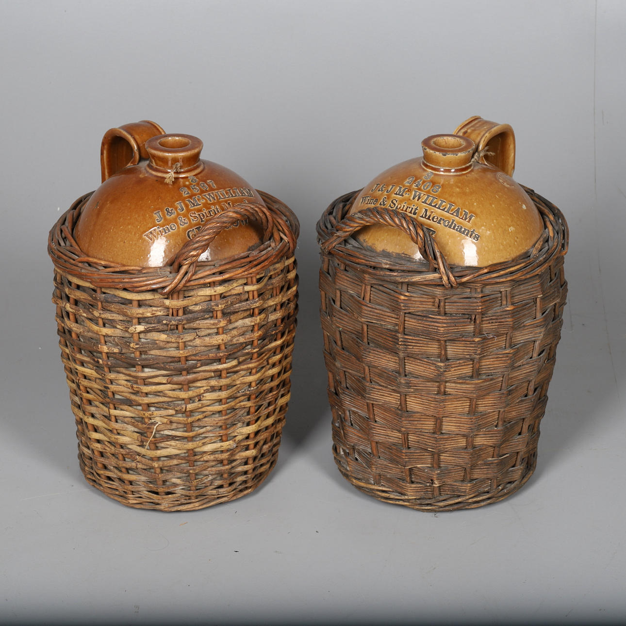 TWO J & J MCWILLIAM WINE FLAGONS IN WICKER BASKETS.