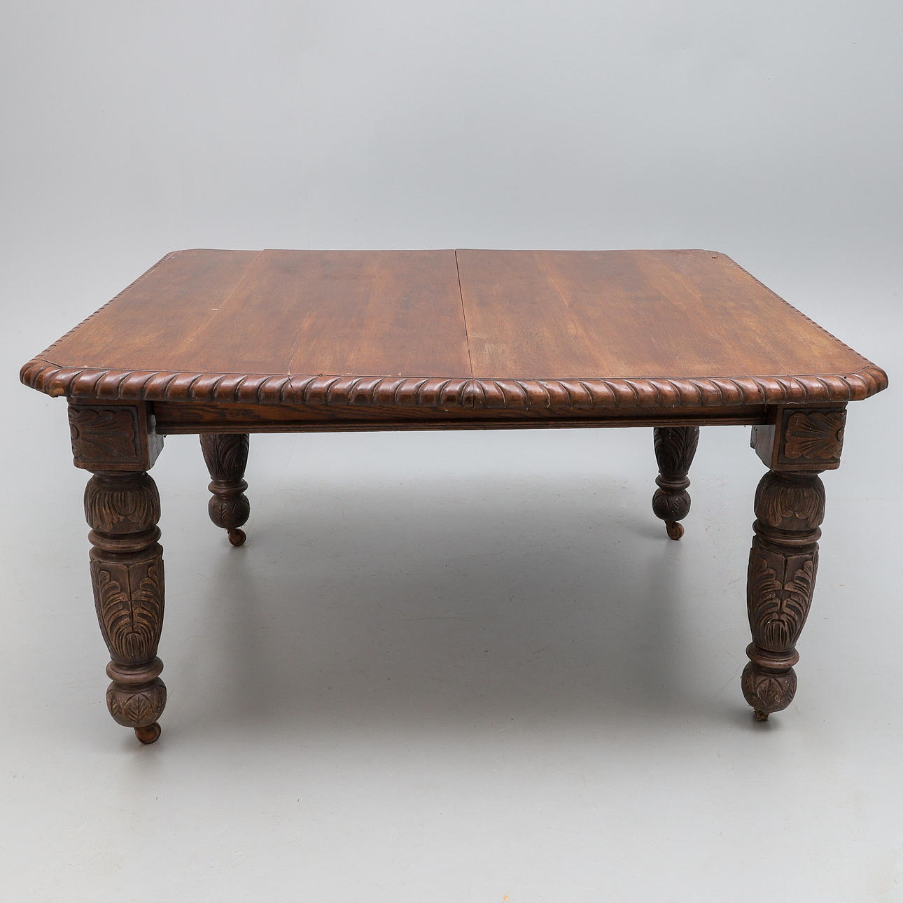 A LATE VICTORIAN OAK EXTENDING DINING TABLE.