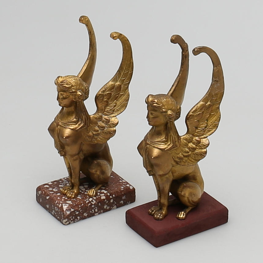 SKULPTURER i mässing på trä/marmorplatta, 2 st, empirstil.