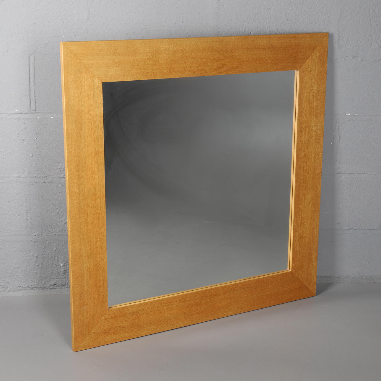 EIN MODERNER WANDSPIEGEL MIT EICHENRAHMEN.