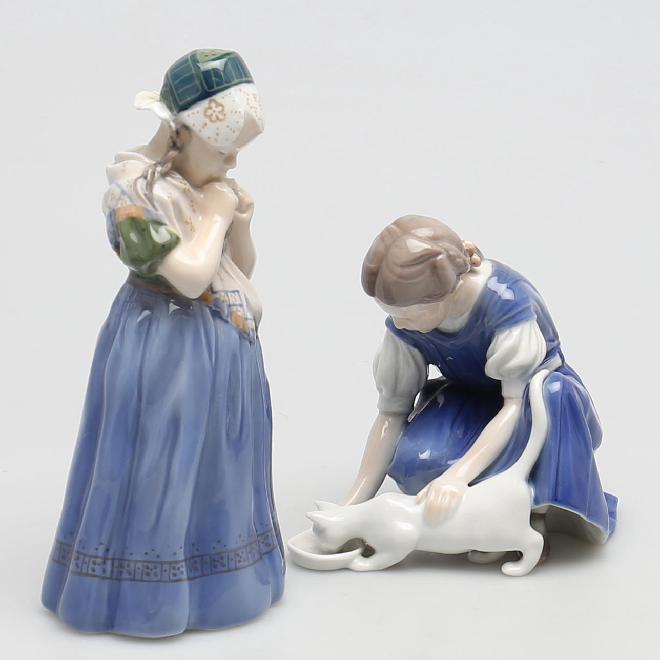 FIGURINER i porslin. 2 st. Flicka med flätor och flicka med katt. Royal Copenhagen och Bing & Gröndahl, Denmark.