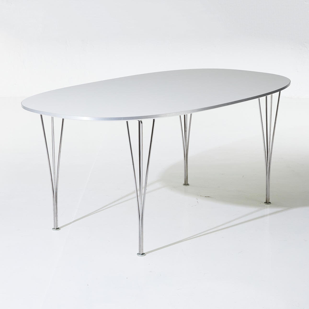 BRUNO MATHSSON & PIET HEIN. "Superellips", Tisch, Tischplatte aus weißem Laminat, vier verchromte Klemmbeine, gemarkt Fritz Hansen"Superellips", Tisch, Tischplatte aus weißem Laminat, vier verchromte Klemmbeine, gemarkt Fritz Hansen.