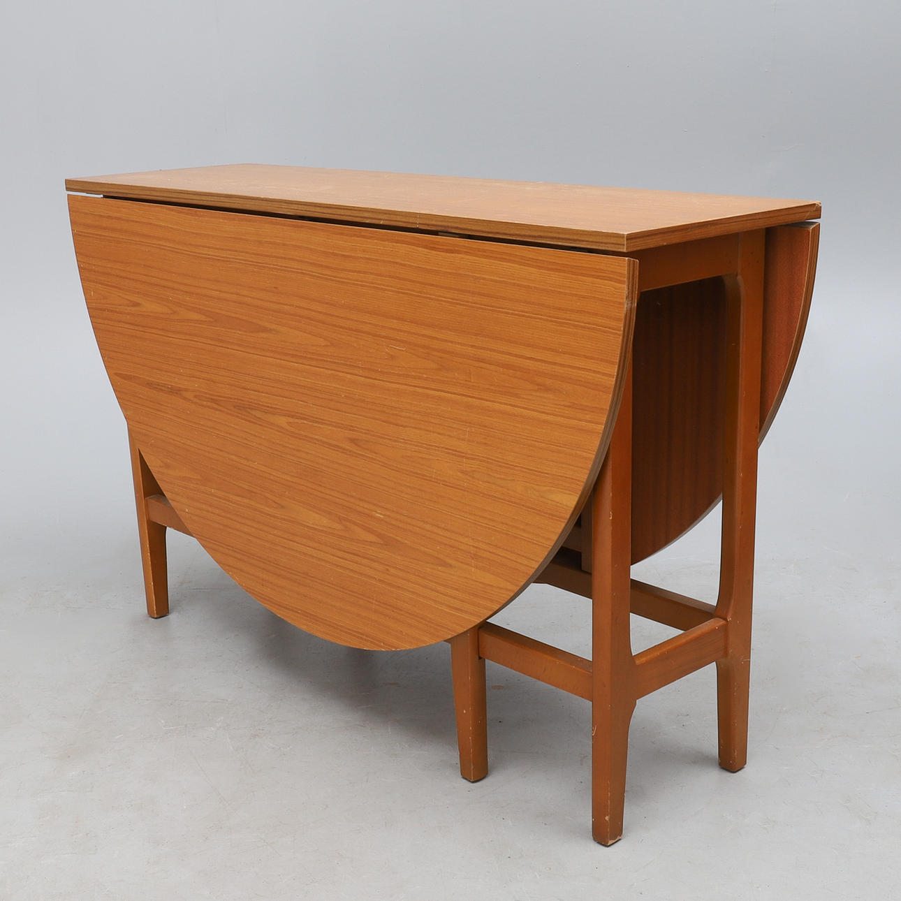 A RETRO TEAK FINISH DROP LEAF DINING TABLE.