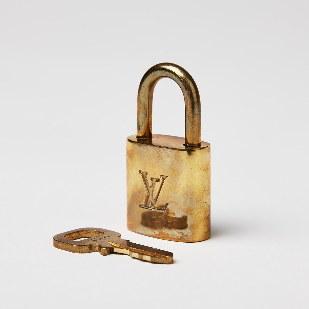 LOUIS VUITTON, candado en metal amarillo con llave.