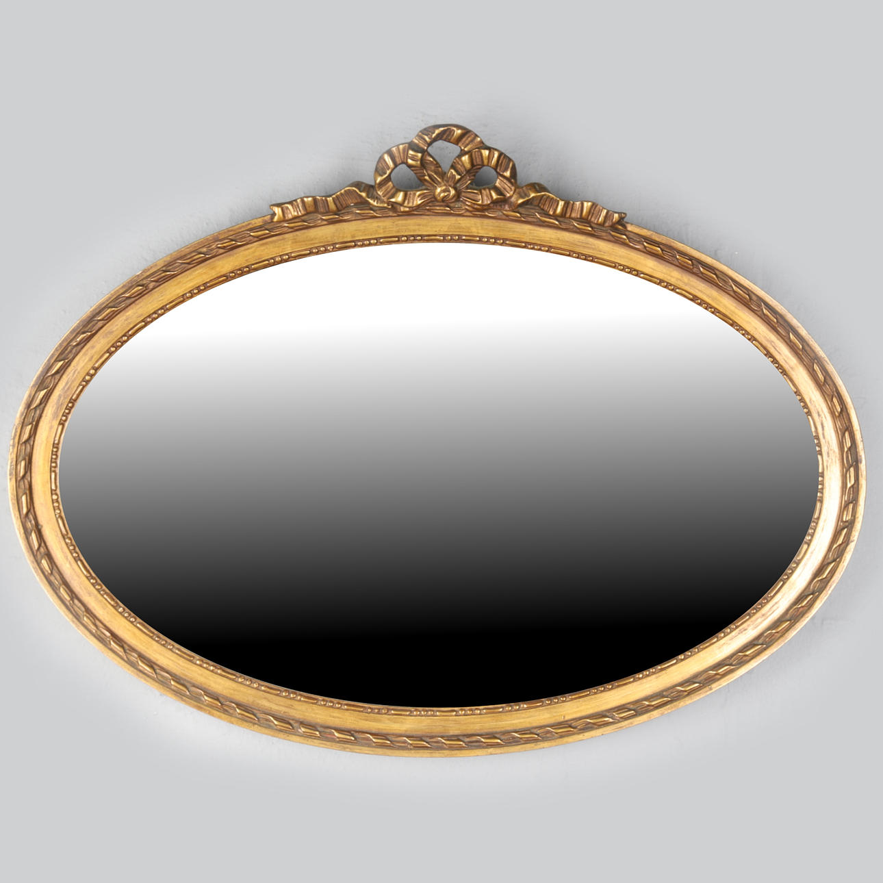 AN OVAL GILT FRAMED WALL MIRROR.