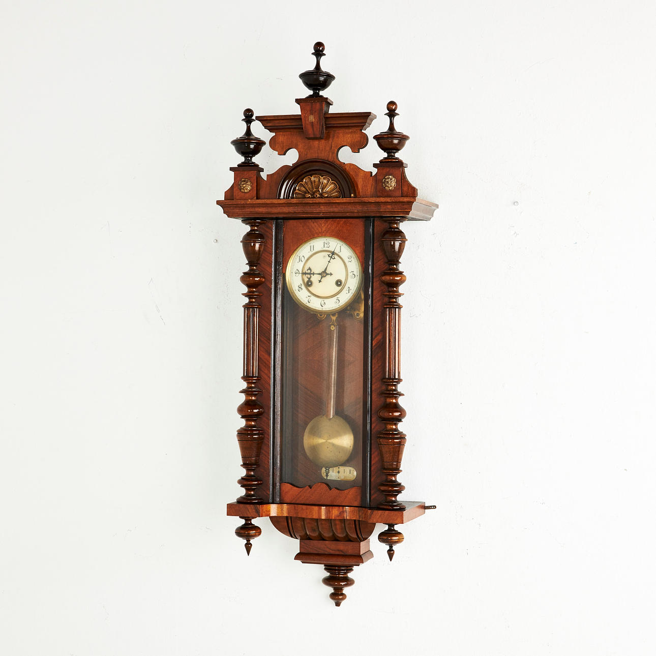 WALL CLOCK / PLUMB REGULATOR, Junghans, case veneered in mahogany, partially turned decoration, enamel dial with Arabic numerals, first half of the 20th century.