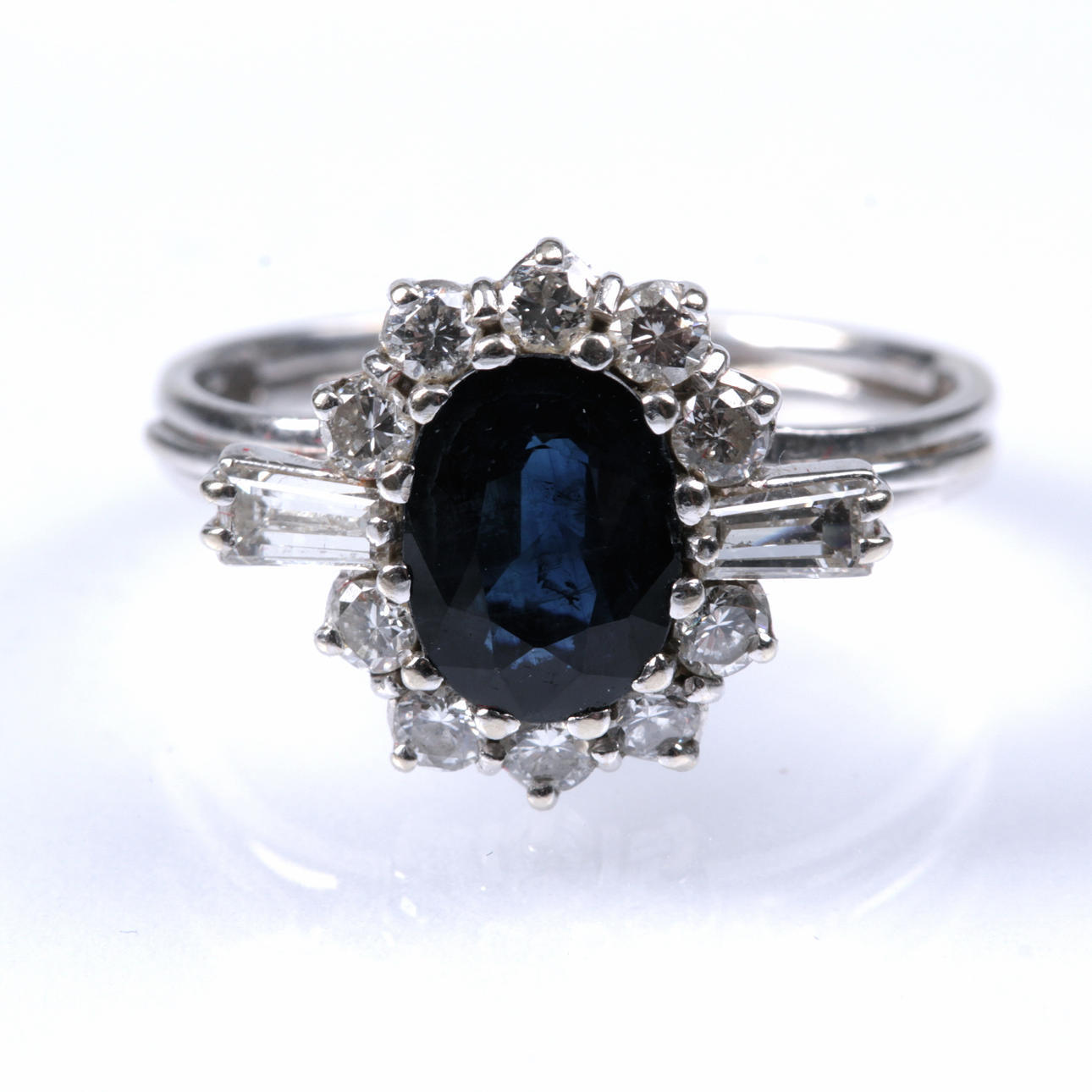 RING, 18 kt vitguld med en stor safir om 1,8 ct. 10 runda och 2 trapetsslipade diamanter om tot 0,80 ct.