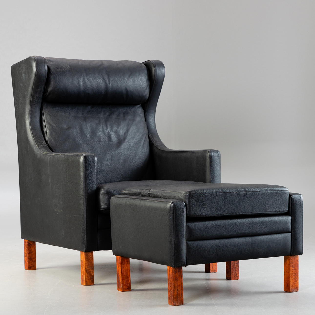 Schwarzer Ledersessel mit Hocker.