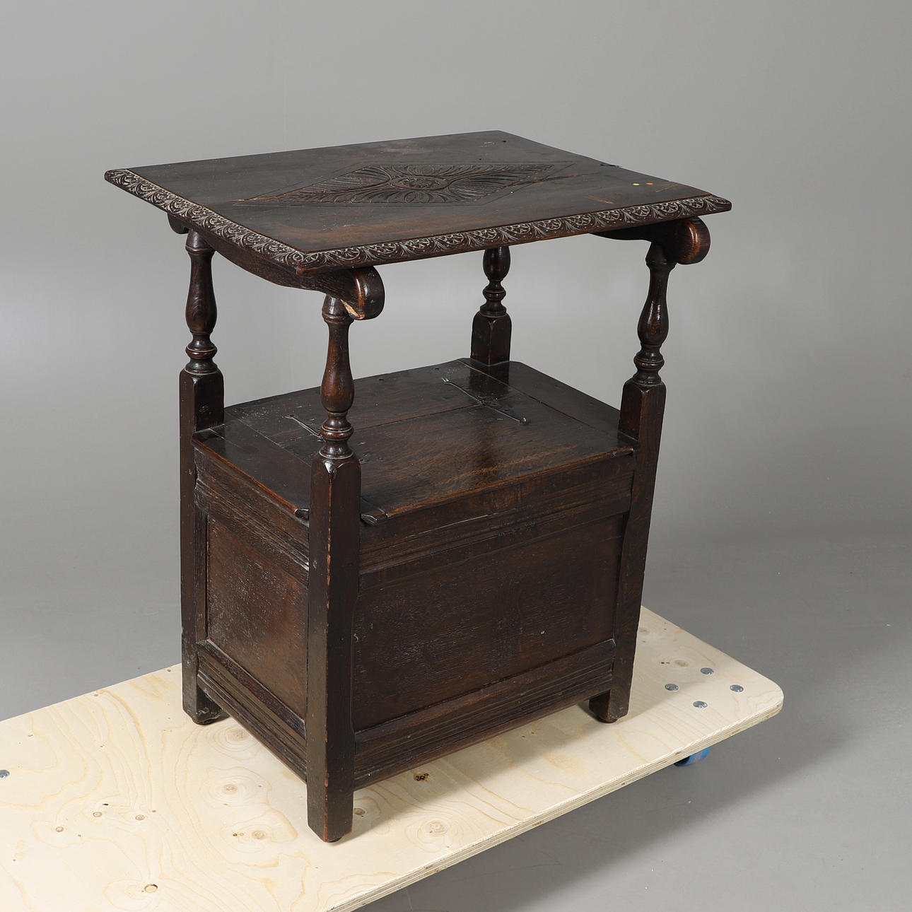 A CARVED OAK MONKS CHAIR.