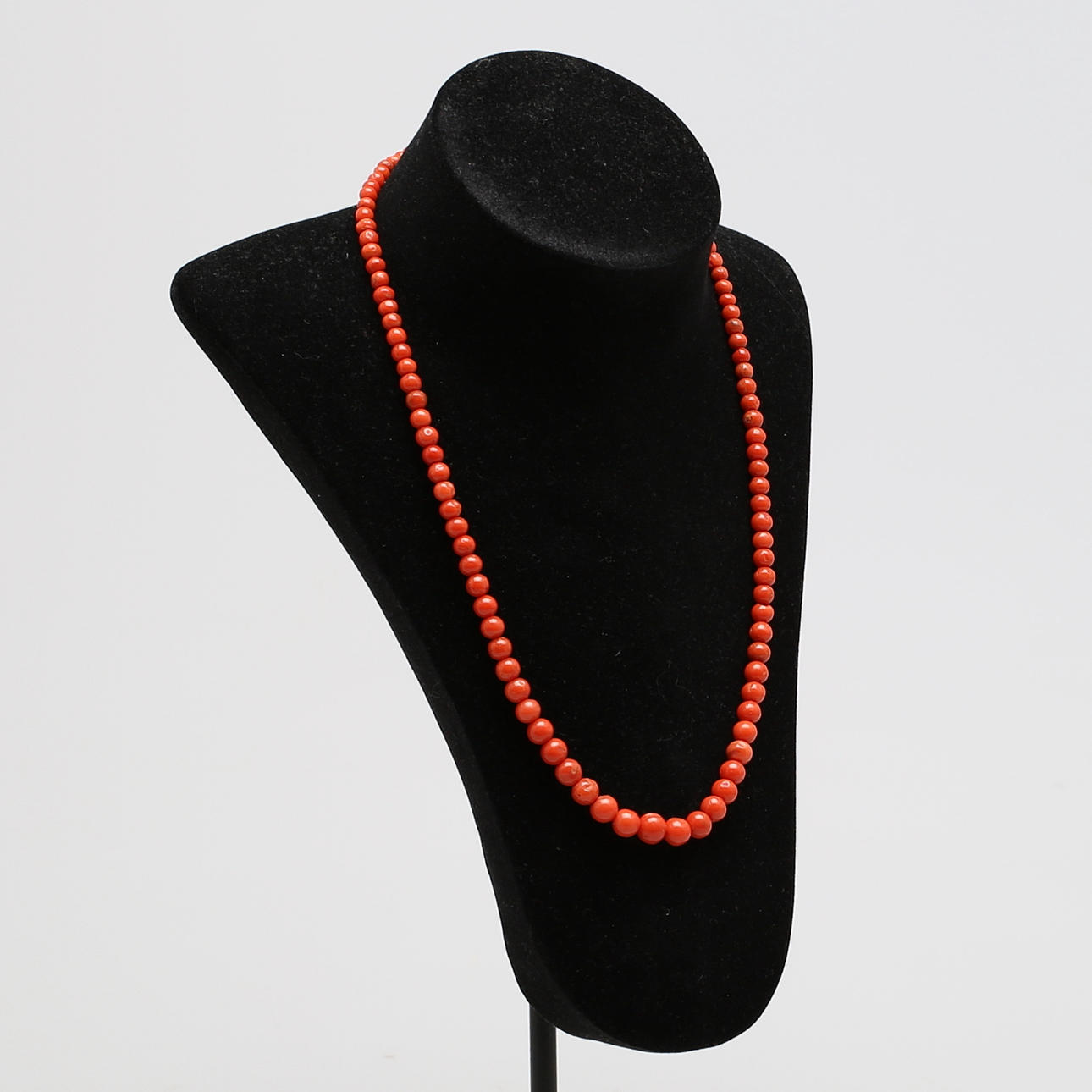 COLLIER med svagt doserade kulor av röd korall, lås i förgyllt silver.