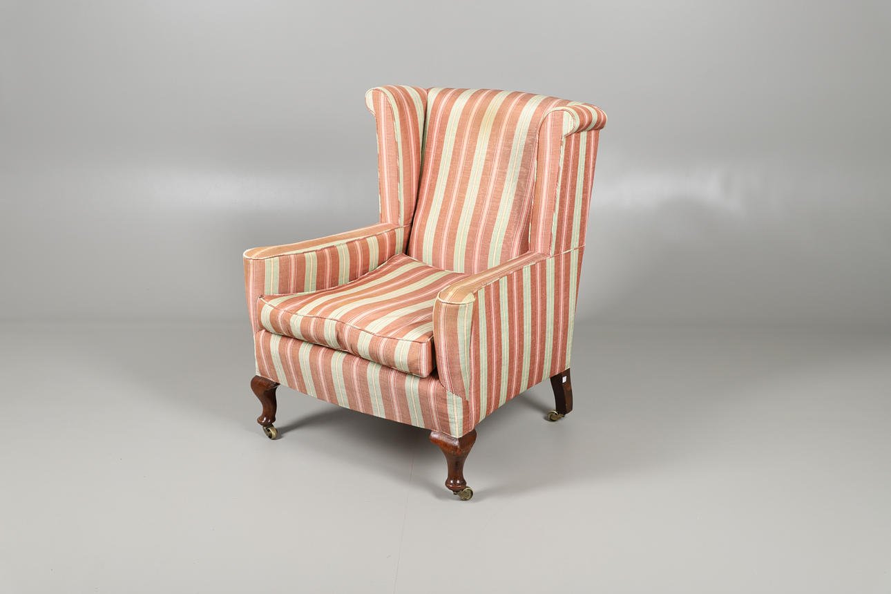 UN SILLÓN DE OREJAS TAPIZADO.