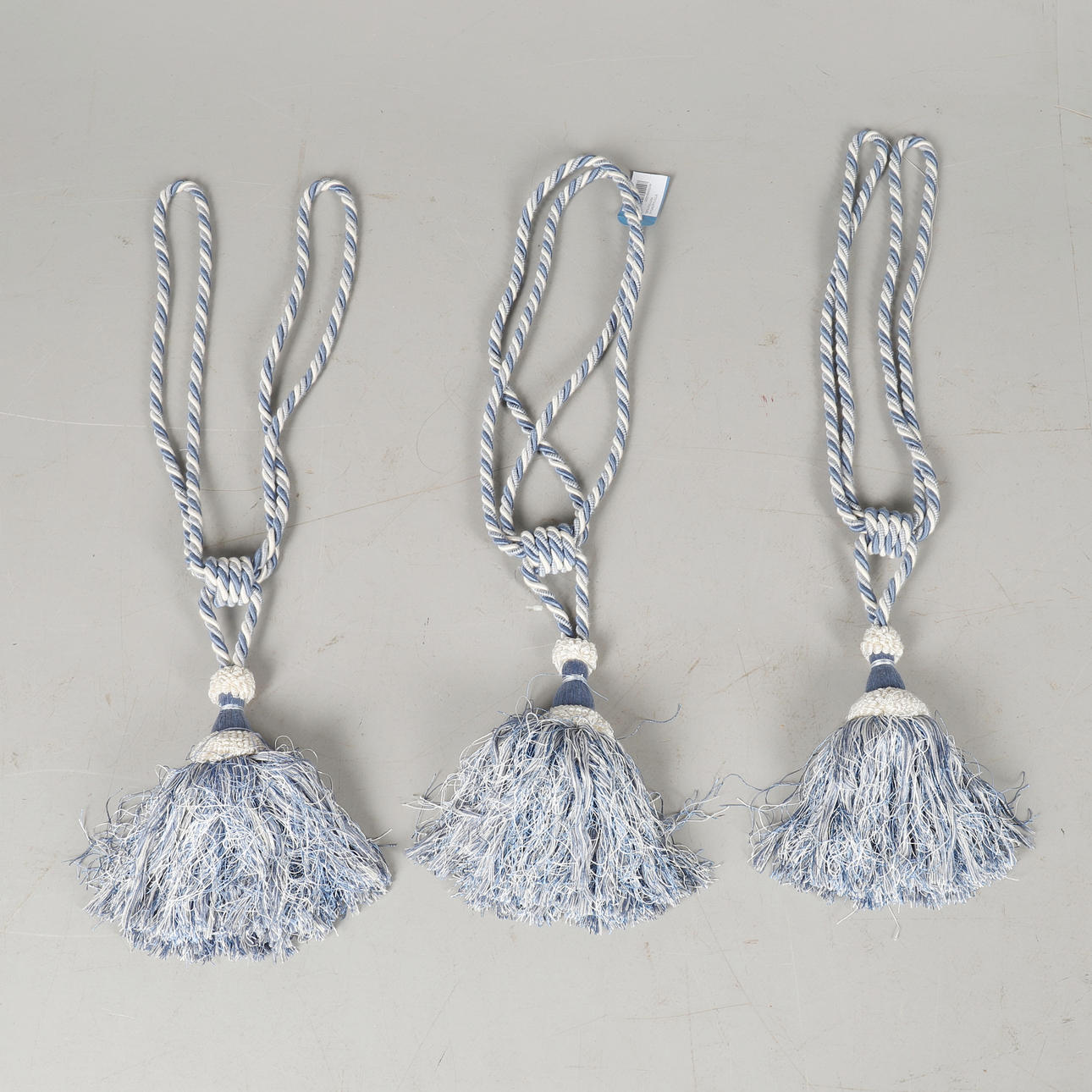 THREE BLUE CURTAIN TIEBACKS WITH TASSELS.