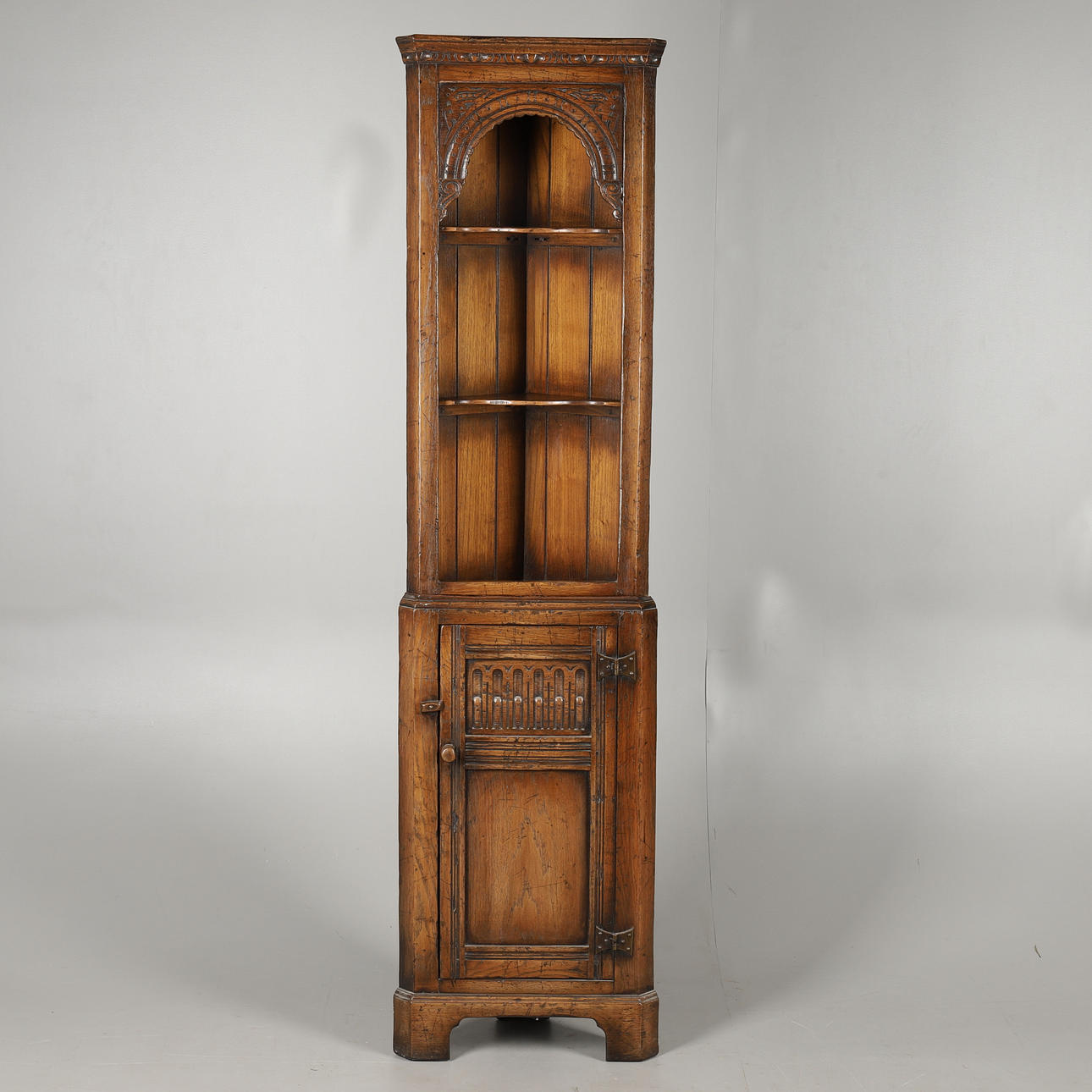 A REPRODUCTION CARVED OAK TWO PART CORNER CUPBOARD.