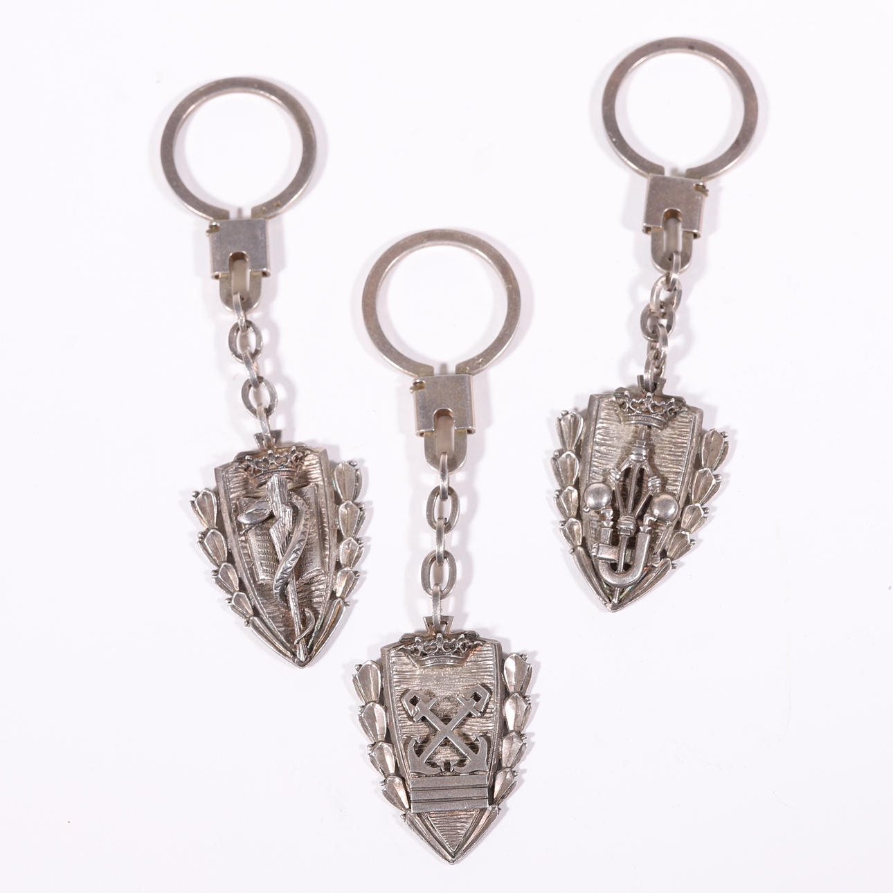 THREE KEYCHAINS WITH HERALDIC SHIELD IN SILVER.