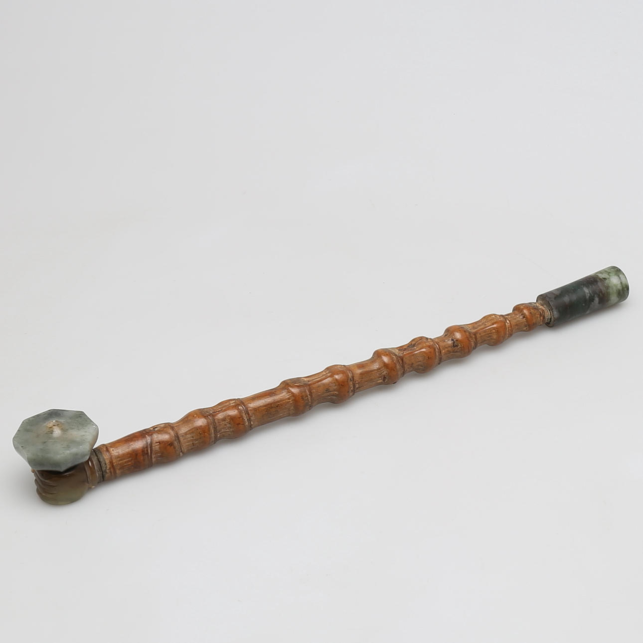 PIPA, Bambooträ med jade. Skuret huvud i form av hand hållande oljelampa. Munstycke även i jade. 1900-tal.