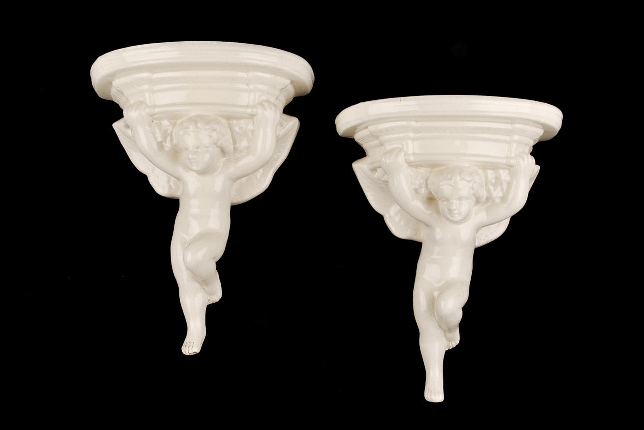 ”ENGELSKA MAJOLICA 2 VÄGGKONSOLER I FORM AV PUTTI”.