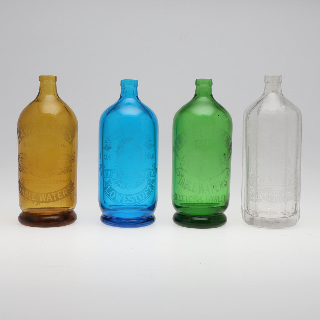 FOUR DECORATIVE COLOURED GLASS BOTTLES.