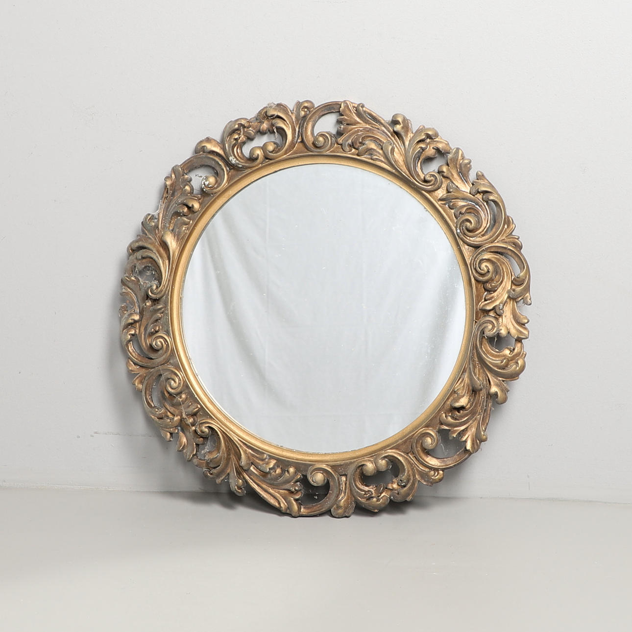 A ROUND GILT FRAMED WALL MIRROR.