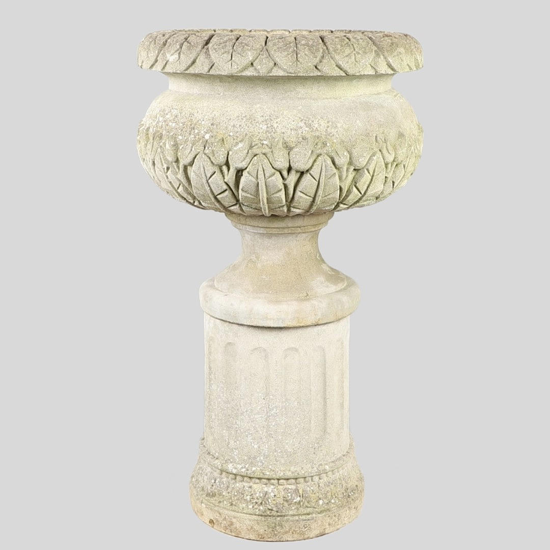 A CONCRETE PLANTER ON A SOCLE AND FLUTED CYLINDRICAL BASE.
